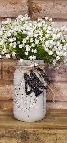 a mason jar filled with white flowers on top of a wooden table