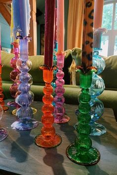 there are many different colored glass candles on the table in front of the couches