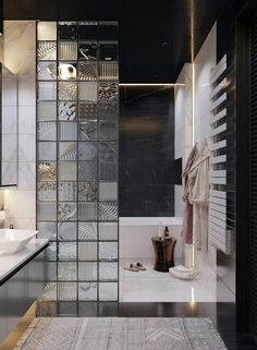 a modern bathroom with black and white tile, glass partitions, and marble flooring