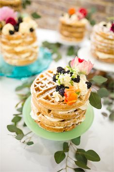 a stack of waffles topped with fruit and flowers on top of a green plate