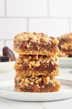 three pieces of granola bar stacked on top of each other in front of a white plate