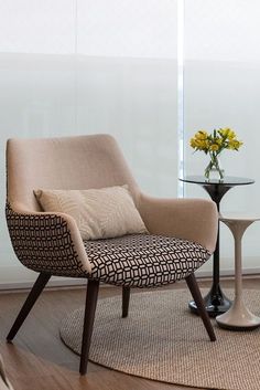 a chair and table in a room with a flower vase on the floor next to it