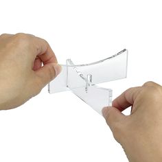 two hands holding a clear plastic object with one hand and the other is pulling it out