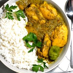 a white bowl filled with rice and meat covered in green sauce next to cilantro