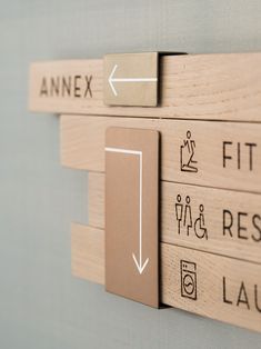 a close up of a wooden sign on a wall with arrows pointing in different directions