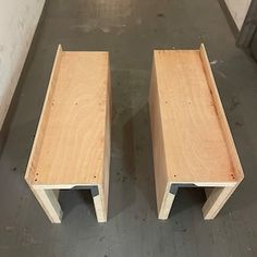 two wooden benches sitting next to each other on a floor in a room with white walls