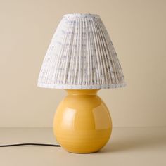 a yellow table lamp with a white shade