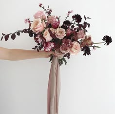 a woman holding a bouquet of flowers in her hand with the stems still attached to it