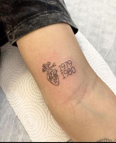 a person with a tattoo on their arm that reads 1950 and has flowers in the shape of a heart