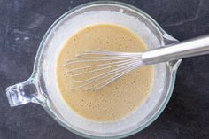 a blender filled with brown liquid and whisk in it's glass bowl