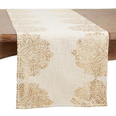 a table with a white and gold table runner on it's side, next to a wooden bench