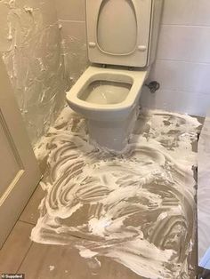 a white toilet sitting on top of a bathroom floor covered in plastic wrap next to a sink