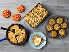 an assortment of baked goods displayed on a wooden table, including pies and muffins