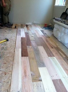 two men are working on the floor in a house that is being remodeled with wood planks