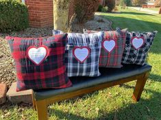 four pillows with hearts on them sitting on a bench