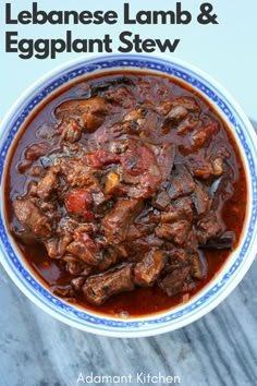 a bowl filled with beef and eggplant stew on top of a wooden table