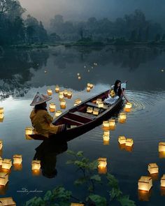 two people in a row boat surrounded by floating lanterns