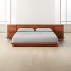 a bed sitting on top of a wooden frame in a room with white walls and flooring