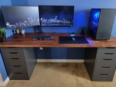 two computer monitors sitting on top of a wooden desk