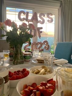 a table filled with plates and bowls full of strawberries, bananas, raspberries