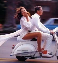 a man and woman riding on the back of a scooter