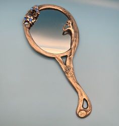 a close up of a gold colored mirror with flowers on the handle and an ornate frame