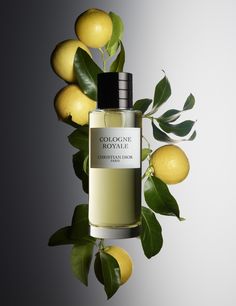 a bottle of cologne sitting next to some lemons on a branch with green leaves