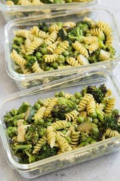 three plastic containers filled with pasta and broccoli on top of a marble counter