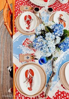 the table is set with blue and white plates, silverware, and hydrangeas