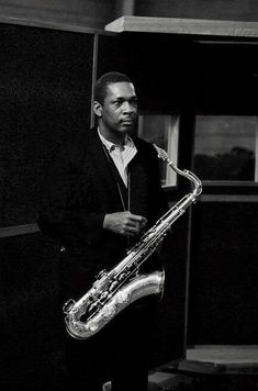 a man in a suit and tie holding a saxophone