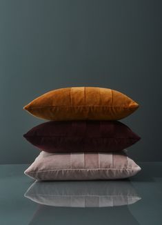 three pillows stacked on top of each other in front of a gray wall and floor