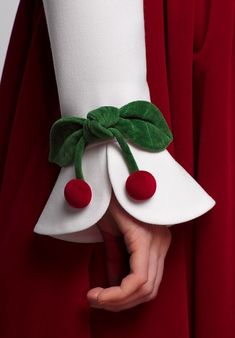 a person in a red dress holding onto a white object with green leaves on it