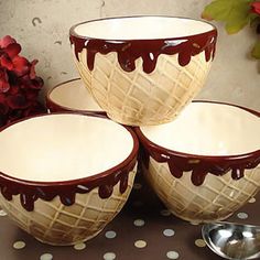 four bowls with chocolate drizzled on them and spoons next to each other