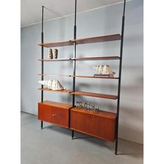 a bookcase with shelves and vases on it in an empty room next to a wall