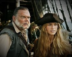 a man and woman in pirate costumes on the deck of a ship looking at something