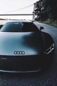 a black car parked on the side of a road next to a body of water