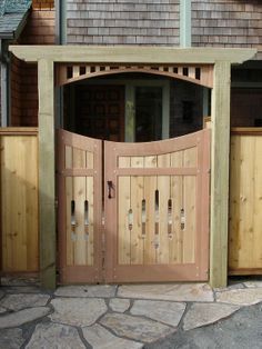 a large wooden gate is open on the side of a house with stone flooring