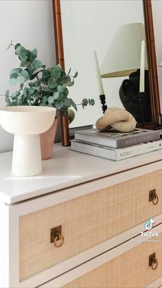 a white dresser topped with a mirror next to a lamp