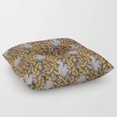 a square pillow with squirrels and leaves printed on it, sitting in front of a white background