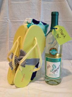 a bottle of wine and some flip flops on a white table with a blue towel