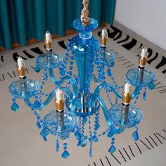 a blue chandelier with several candles in it on a table next to a curtain