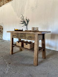 a wooden table with baskets on it in front of a white wall and stone stairs