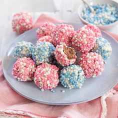 a plate full of colorful sprinkled donuts with a spoon in the background