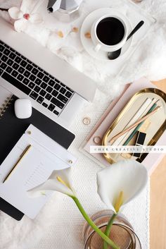 a laptop computer sitting on top of a desk next to a vase filled with flowers