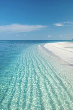 the water is crystal blue and clear with white sand on it's sides, as well as an island in the distance