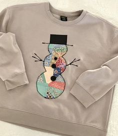 a grey sweatshirt with a patchwork snowman on it