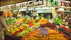 a fruit and vegetable stand with people shopping in the storefronts at night time