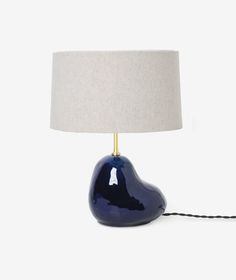 a blue lamp with a white shade on it and a black cord plugged into the base