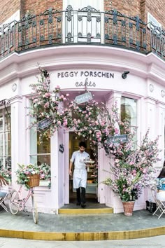 a man standing in front of a pink building with lots of flowers growing out of it