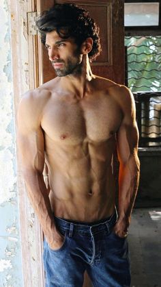 a shirtless man standing in front of a door with his hands on his hips